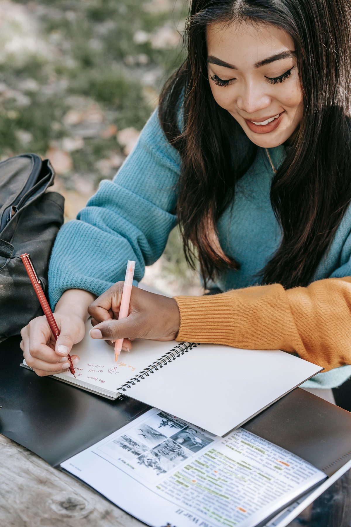 Young diverse women writing in notebook while studying