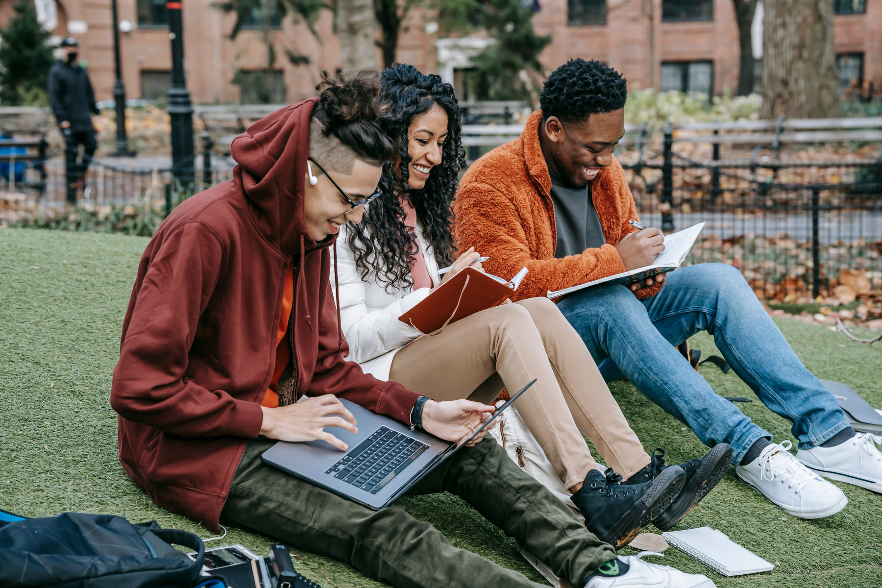 Cheerful diverse classmates studying in park